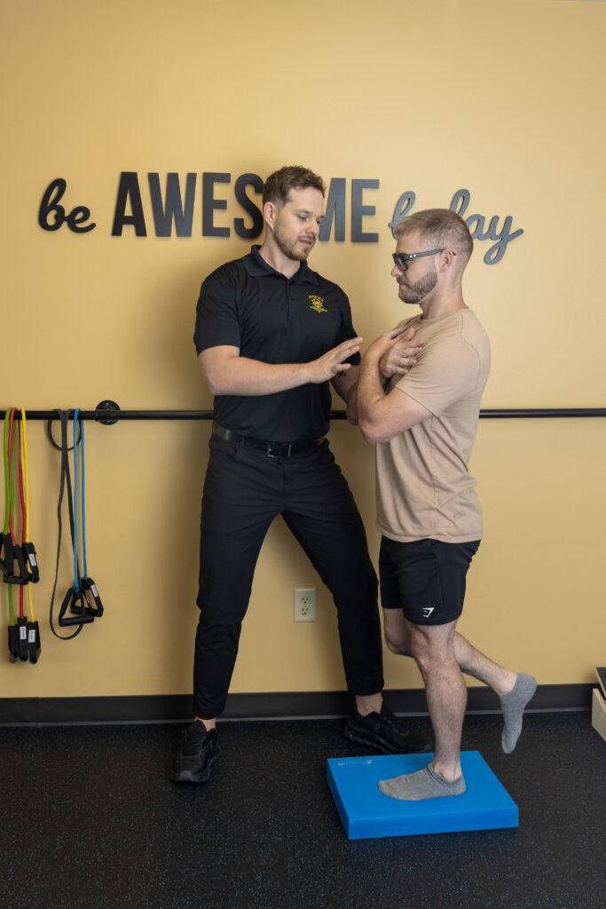 Physical therapist helping man with balance exercise