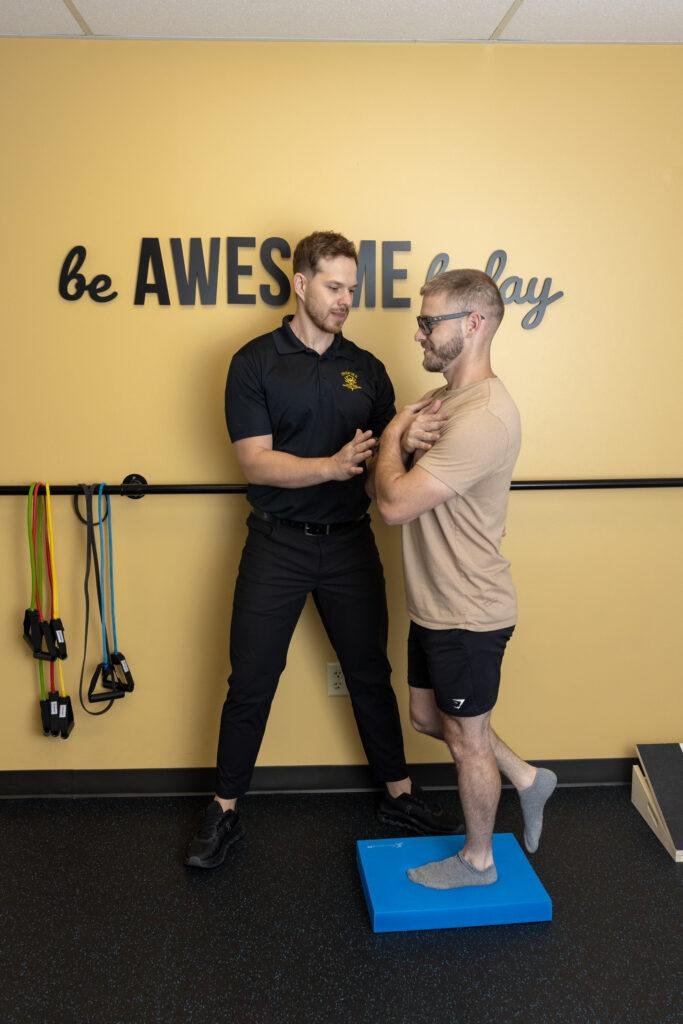 Physical therapist assisting man with balance exercise