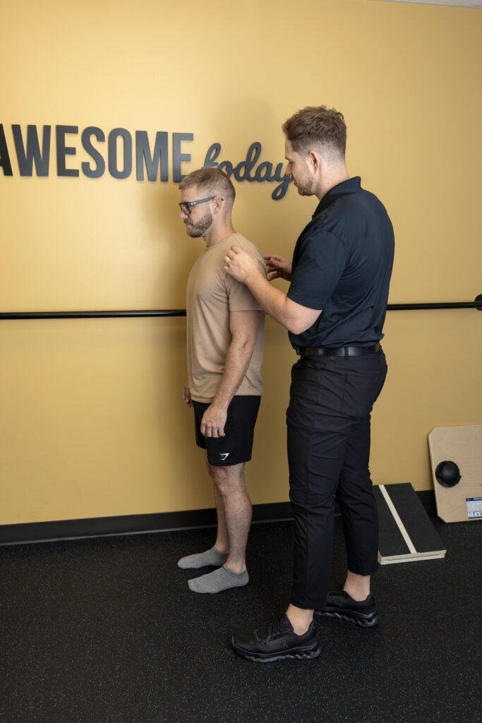 Trainer assessing man's posture during session