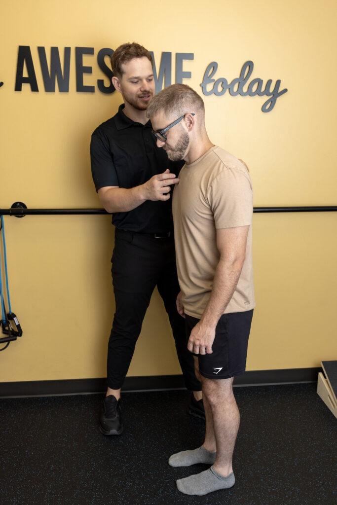 Trainer assisting man with posture exercise
