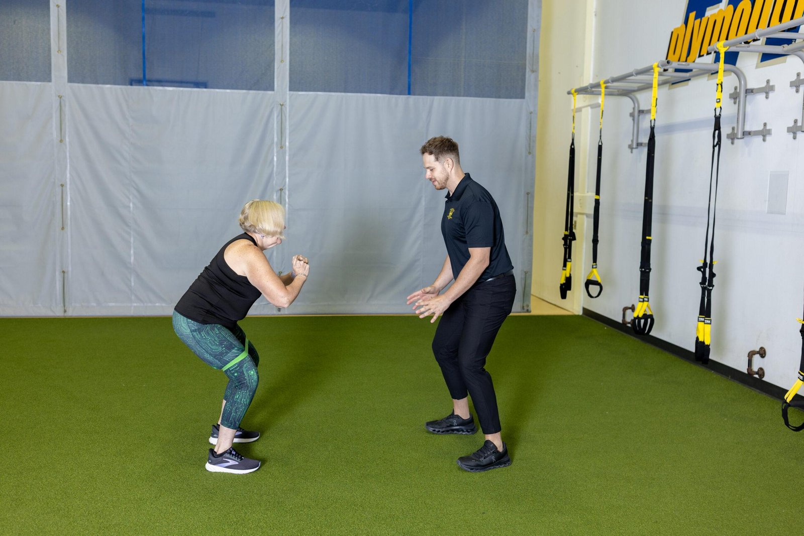 Trainer coaching woman performing therapeutic exercise indoors