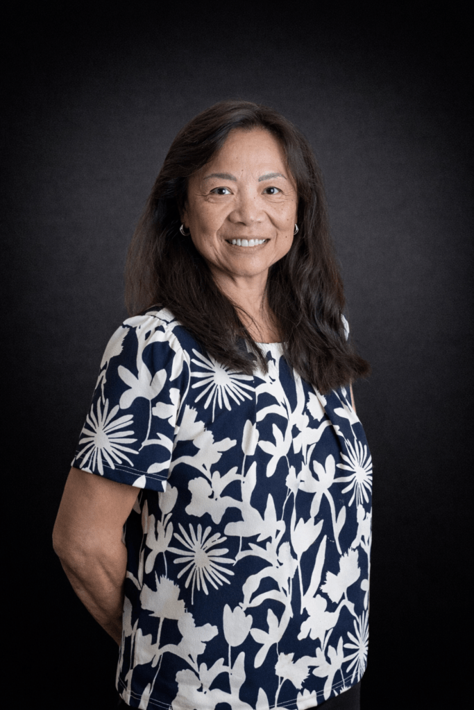 Smiling woman in floral shirt against dark background